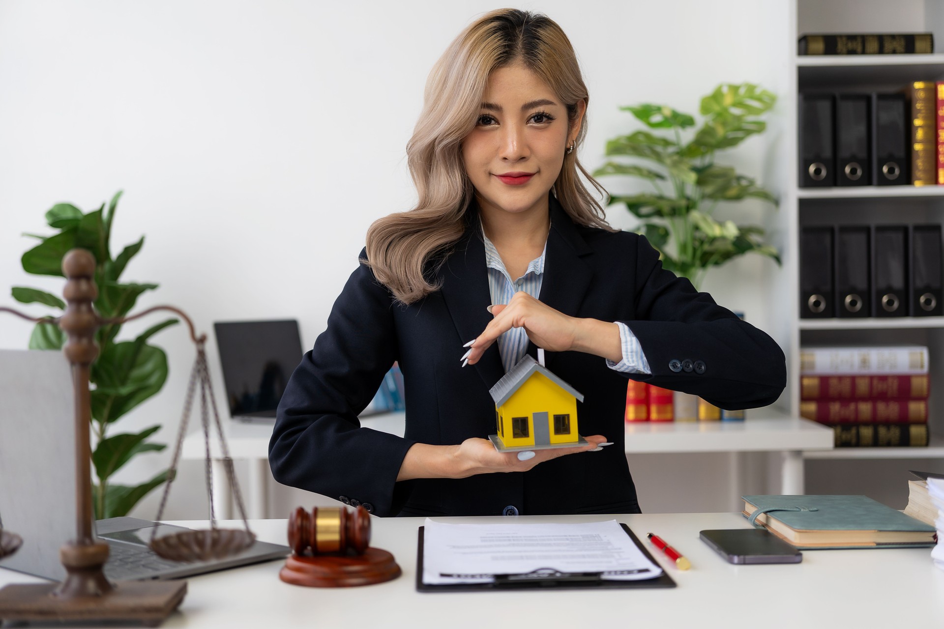 Leilão de Imóveis Mão da mulher segurando martelo e casa modelo, advogado imobiliário em venda de casa, finanças e execução hipotecária, conceito de propriedade.